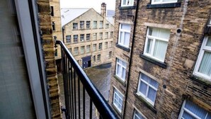 Vista desde un balcón que da a una calle estrecha con edificios de ladrillo tradicionales, con numerosas ventanas y una puerta a la vista.