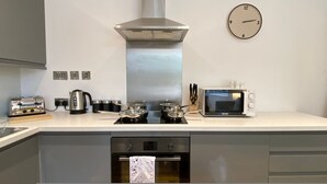 Una cocina moderna con campana extractora de acero inoxidable, microondas, hervidor y tostadora.