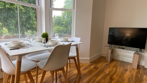 Un comedor moderno con un gran ventanal, un televisor de pantalla plana y suelo de madera.