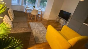 Una sala de estar con sofá, mesa de centro, televisor y un comedor con mesa y sillas.