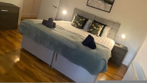 Un dormitorio con cama, mesitas de noche y un cabecero.
