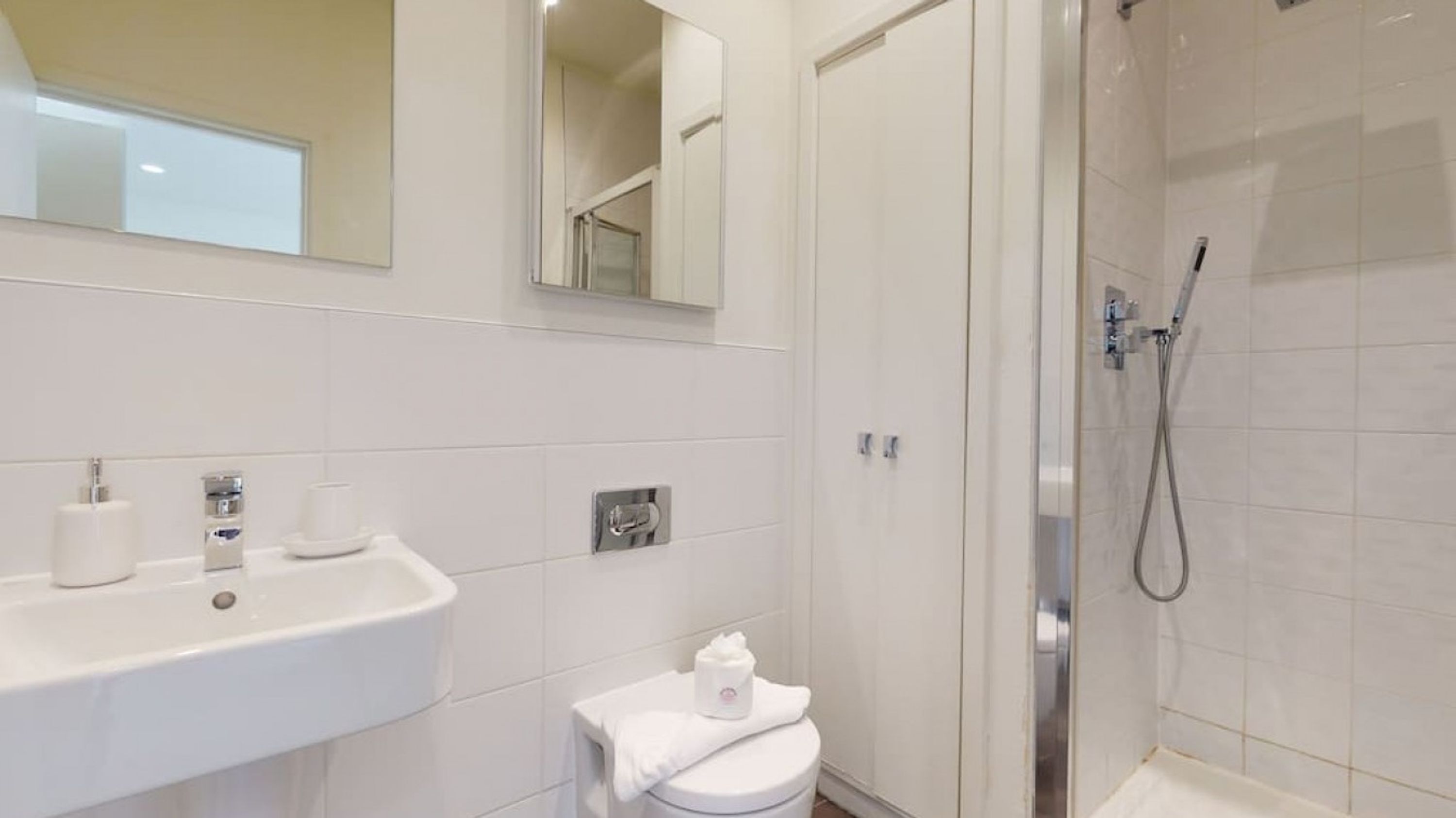Une salle de bain moderne équipée d’un lavabo, de toilettes et d’une douche.