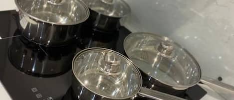 A kitchen with four stainless steel pots on a black induction cooktop.
