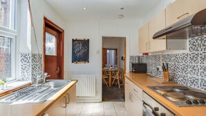 Une cuisine moderne  équipée d’une cuisinière intégrée, d’un évier et d’un coin repas avec une table et des chaises.