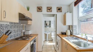 Une cuisine de taille réduite, avec des meubles de rangement en bois, une cuisinière, un évier et une fenêtre.