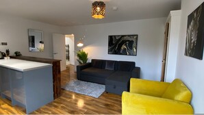 Ein modernes Wohnzimmer mit einem grauen Sofa, einem gelben Sessel und einem schwarzen, abstrakten Gemälde an der Wand.