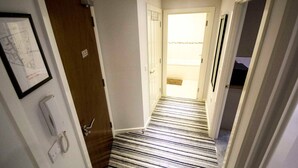 A hallway with a striped carpet leading to a door with a 'NO ENTRY' sign.