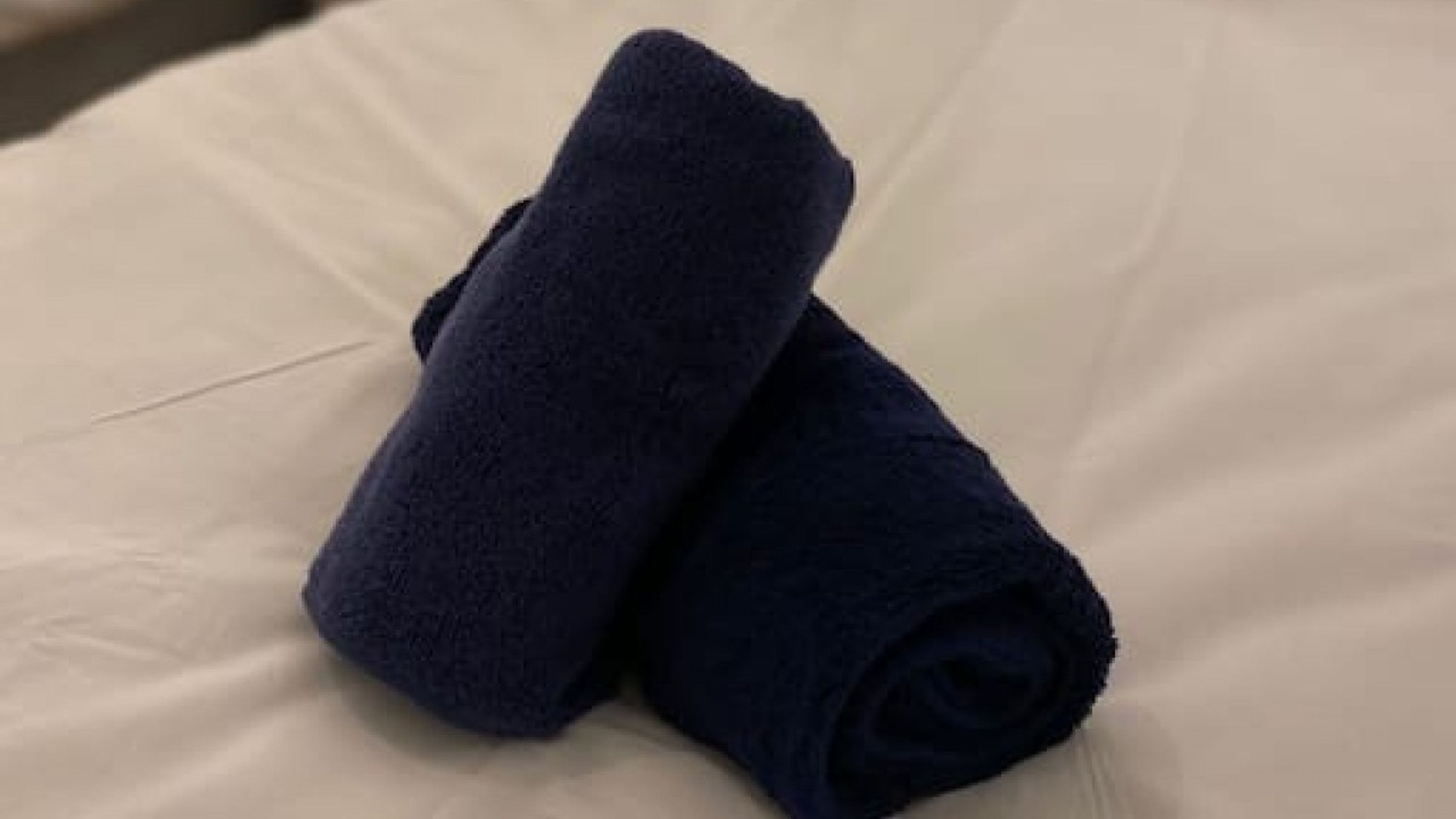 Zwei gerollte Handtücher auf einem Bett.