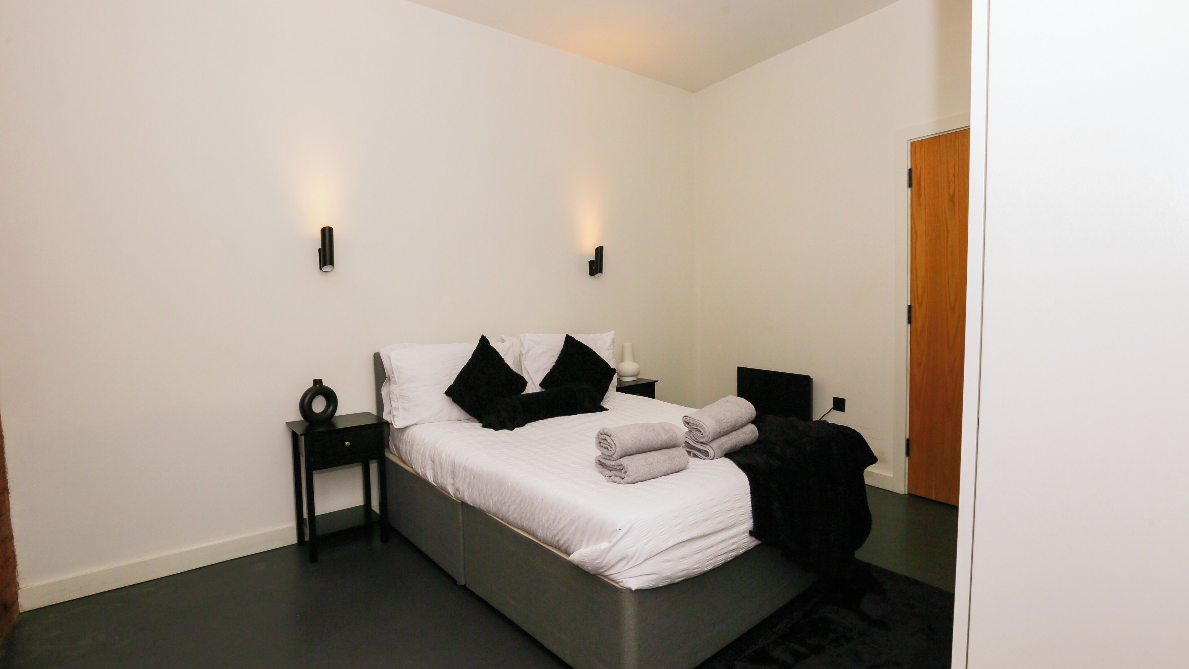 A modern bedroom with a bed, two bedside tables, and a nightstand.