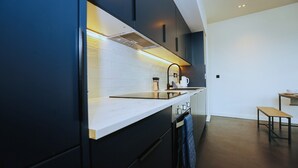 Een moderne keuken met donkere kastjes, een wit aanrechtblad en een ingebouwde oven.