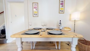 A dining table set with plates, cutlery, and wine glasses, with a loaf of bread and a lamp on the table. - Stayzo Westminster Stylish House Accommodation (Bradford)