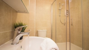 Un baño moderno con ducha envuelta en vidrio, bañera blanca y lavamanos con grifo cromado.