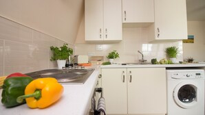 Une cuisine moderne avec des meubles blancs, un évier en acier inoxydable et un lave-linge encastré.