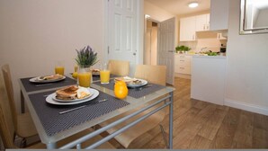 A dining area with a table set for breakfast, including toast, eggs, and orange juice. - Stayzo Castle Point 18 Apartments - Premier Lodge (Southampton)