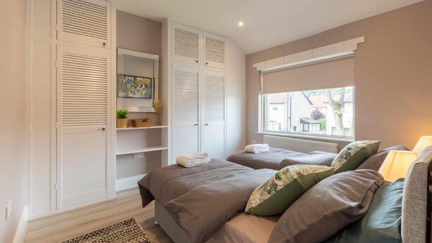Een slaapkamer met twee bedden, een raam met uitzicht en ingebouwde planken met handdoeken.