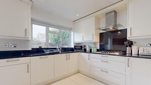 A modern kitchen with white cabinets, a black countertop, and a window providing natural light. - Parlaunt House - 3 Bedroom With Free Parking (Slough)