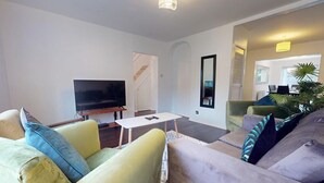 A modern living room with a flat-screen TV, a white coffee table, and two sofas with patterned cushions. - Parlaunt House - 3 Bedroom With Free Parking (Slough)