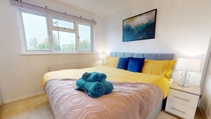 A bedroom with a bed, a nightstand, a window, and a painting on the wall. - Parlaunt House - 3 Bedroom With Free Parking (Slough)