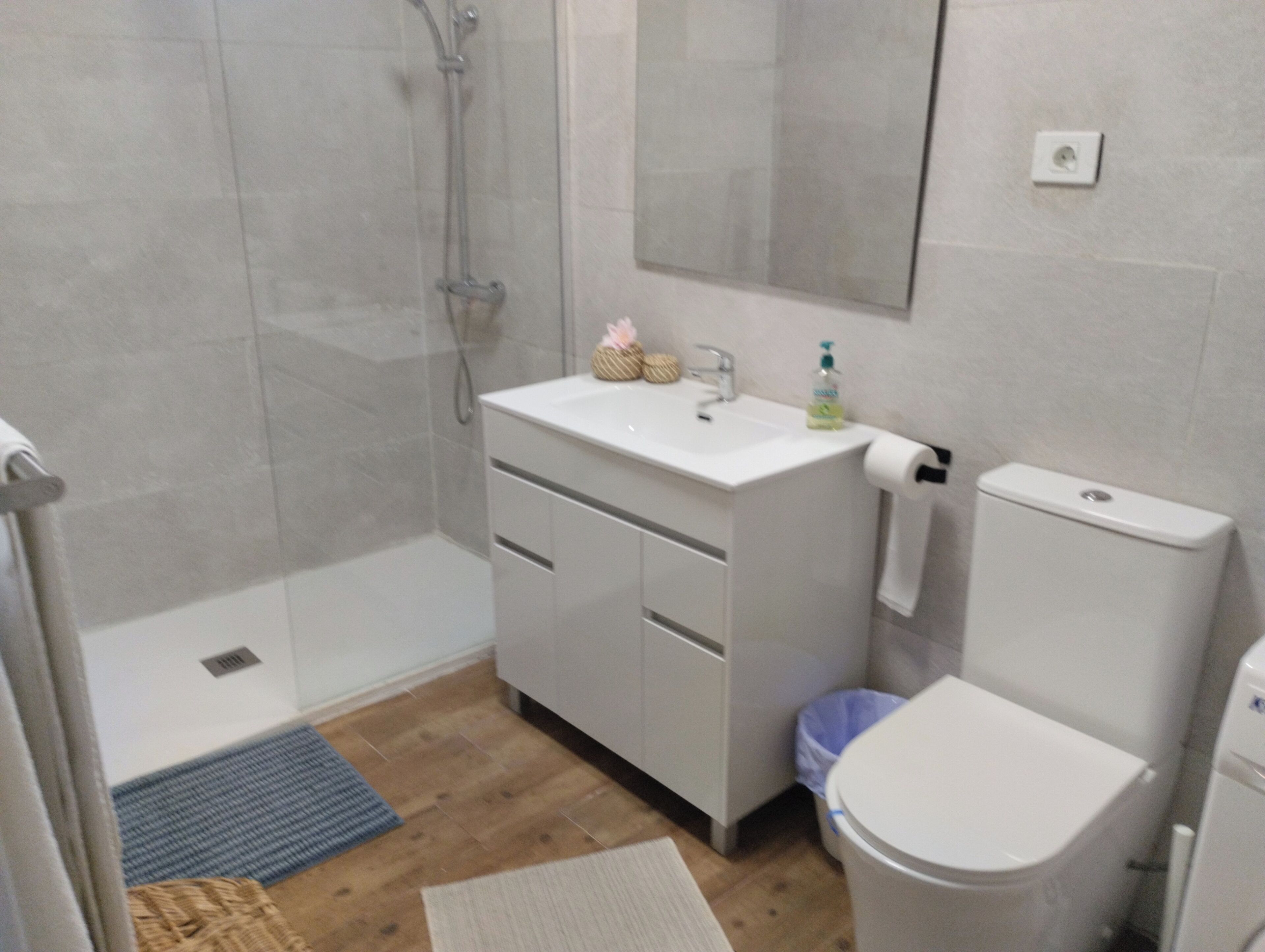 Ein Badezimmer mit Dusche, Waschbecken, Toilette und Spiegel.