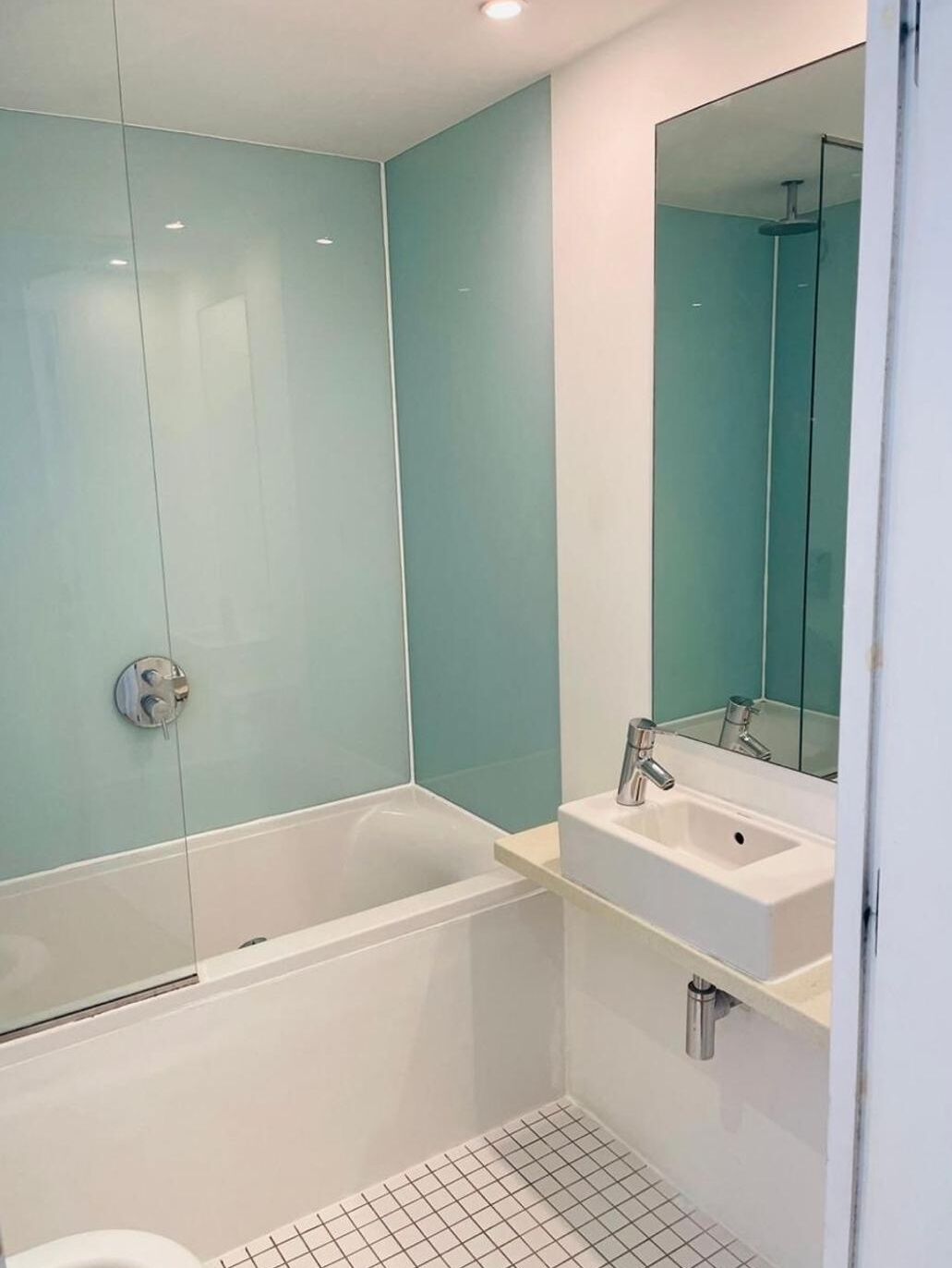 A modern bathroom with a glass-enclosed shower, a white bathtub, and a sink with a mirror above it.