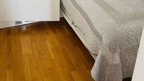 Une petite pièce, de taille modeste, comprenant un lit, une armoire et une porte.