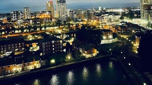 Une vue nocturne d'une ville, avec des bâtiments illuminés et une rivière.