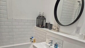 Une salle de bain avec une baignoire, un lavabo, des toilettes et un miroir.