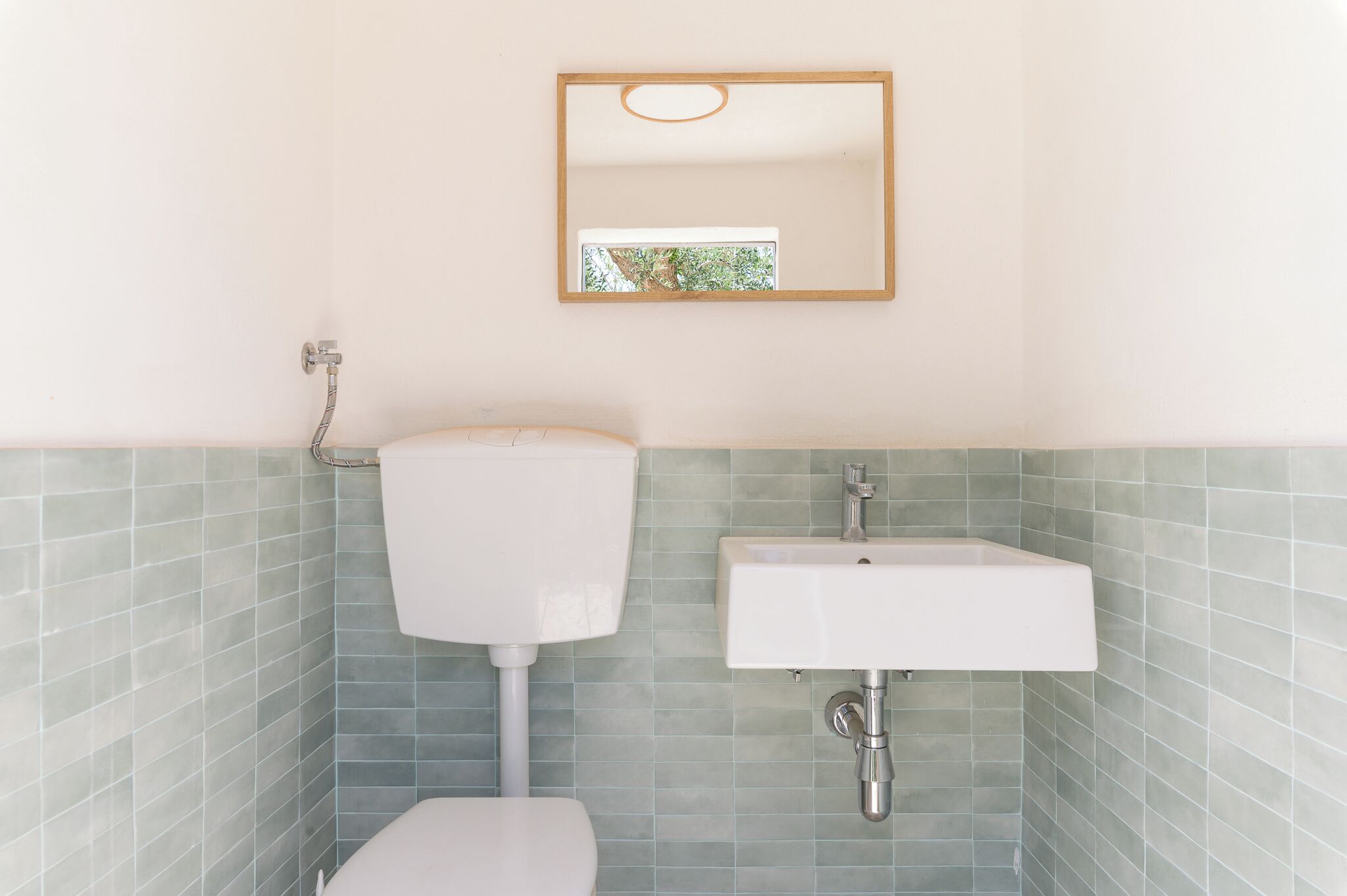 A bathroom with a toilet, a sink, and a mirror.