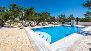 Una piscina al aire libre de temporada, sillones reclinables de piscina