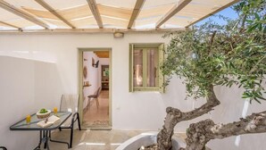 A covered outdoor area with a table, chairs, and a potted tree. - Fantasy Rooms  (Milos)