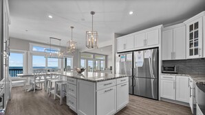 A modern kitchen with white cabinets, stainless steel appliances, and a large island.
