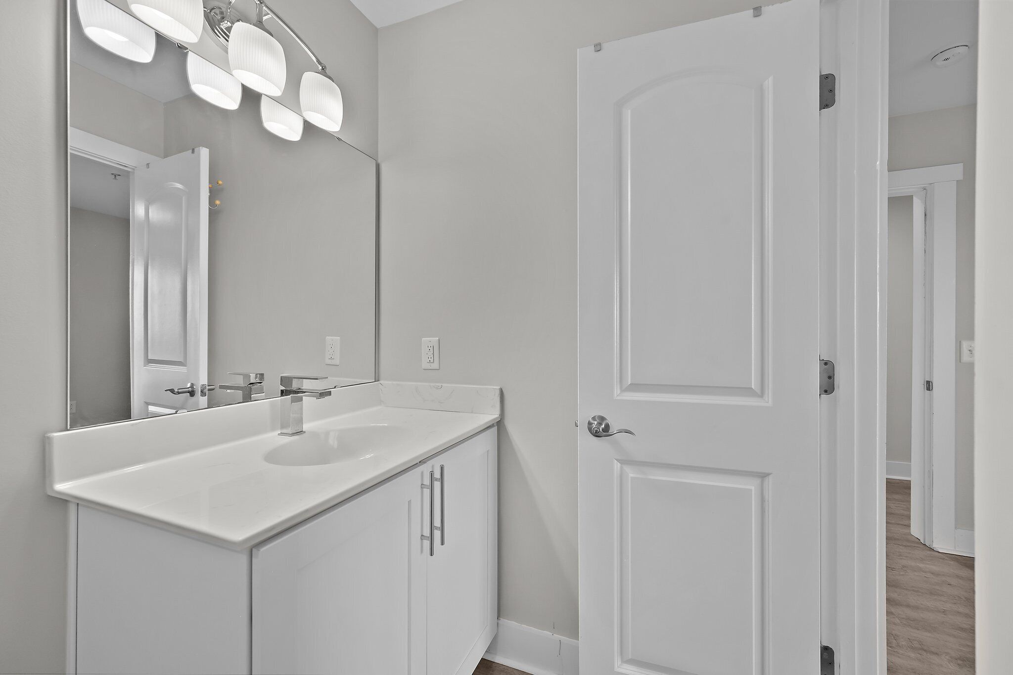 A modern bathroom with a white vanity, a large mirror, and a shower.