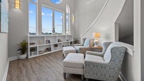 A modern living room with a large window, a built-in bookshelf, and two patterned armchairs.
