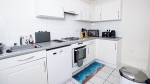 Una cucina moderna con mobili bianchi, piano cottura a gas, lavastoviglie e forno a microonde.