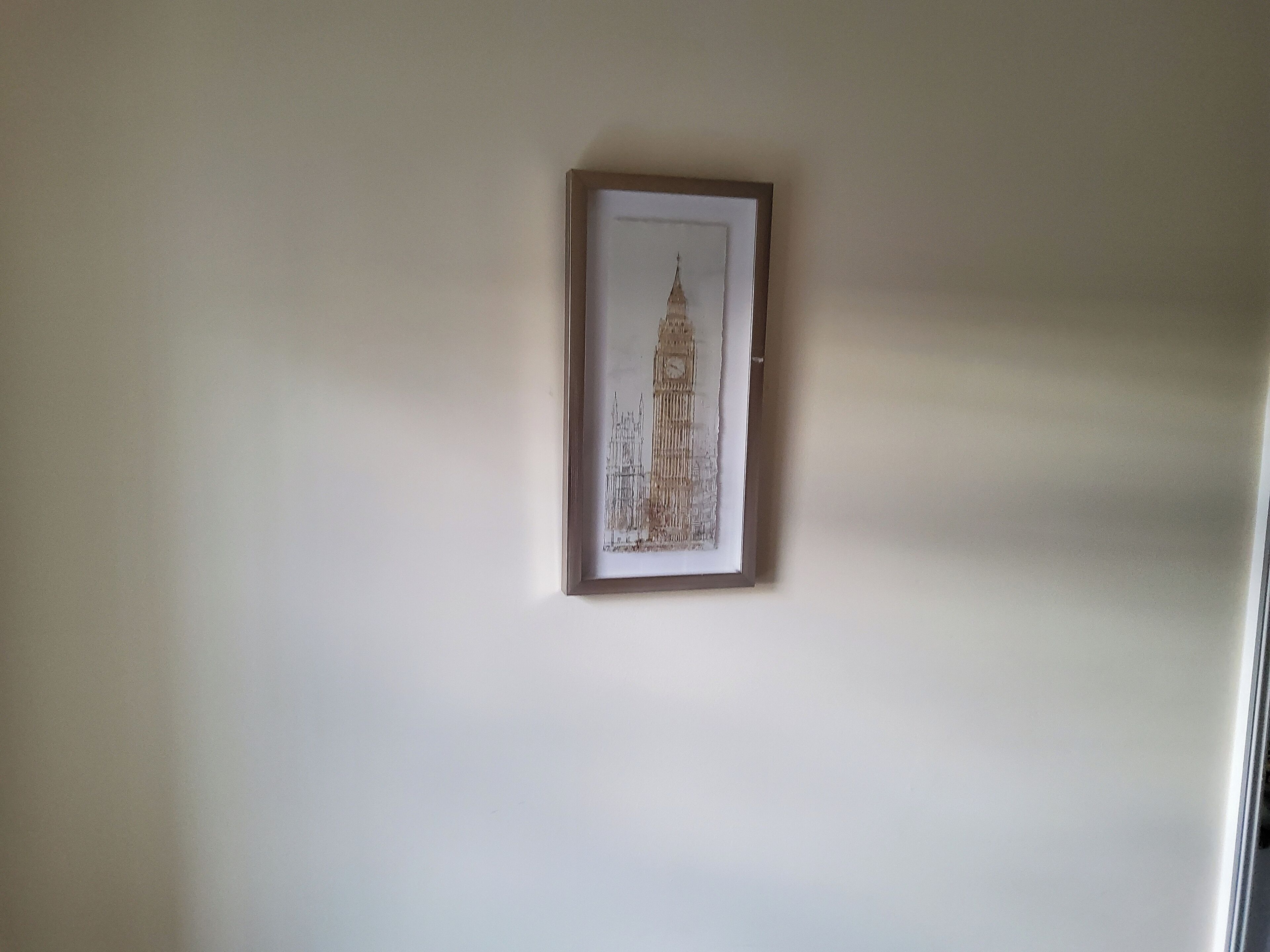 Ein gerahmtes Bild eines Gebäudes an einer schlichten Wand.