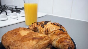 Un piatto con due croissant e un bicchiere di succo d'arancia su un piano di lavoro in cucina.