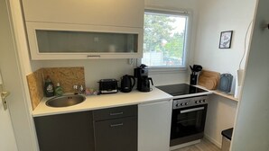 A compact kitchen with a microwave, stove, sink, and a window providing natural light.