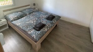 A bedroom with a bed, a nightstand, a lamp, and a painting of a beach scene.