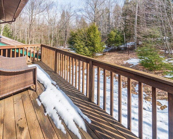 A wooden deck with snow on the floor, surrounded by trees. - Perfect Family Vacation Home in the Mountains (Windham)
