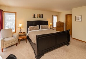 A bedroom with a large bed, bedside tables, a chair, and a dresser. - Perfect Family Vacation Home in the Mountains (Windham)