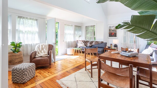 A spacious living room with a wooden floor, a dining table, and a comfortable seating area.