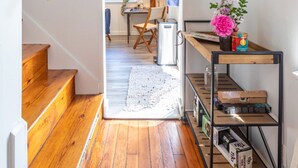 A wooden staircase leading to a room with a desk, chair, and a shelf with books and a vase of flowers.
