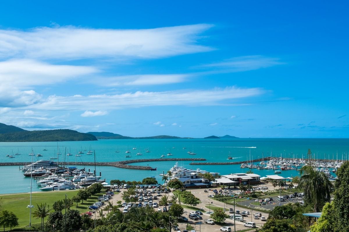 Un port de plaisance avec des bateaux, un espace de stationnement et une vue sur la côte.