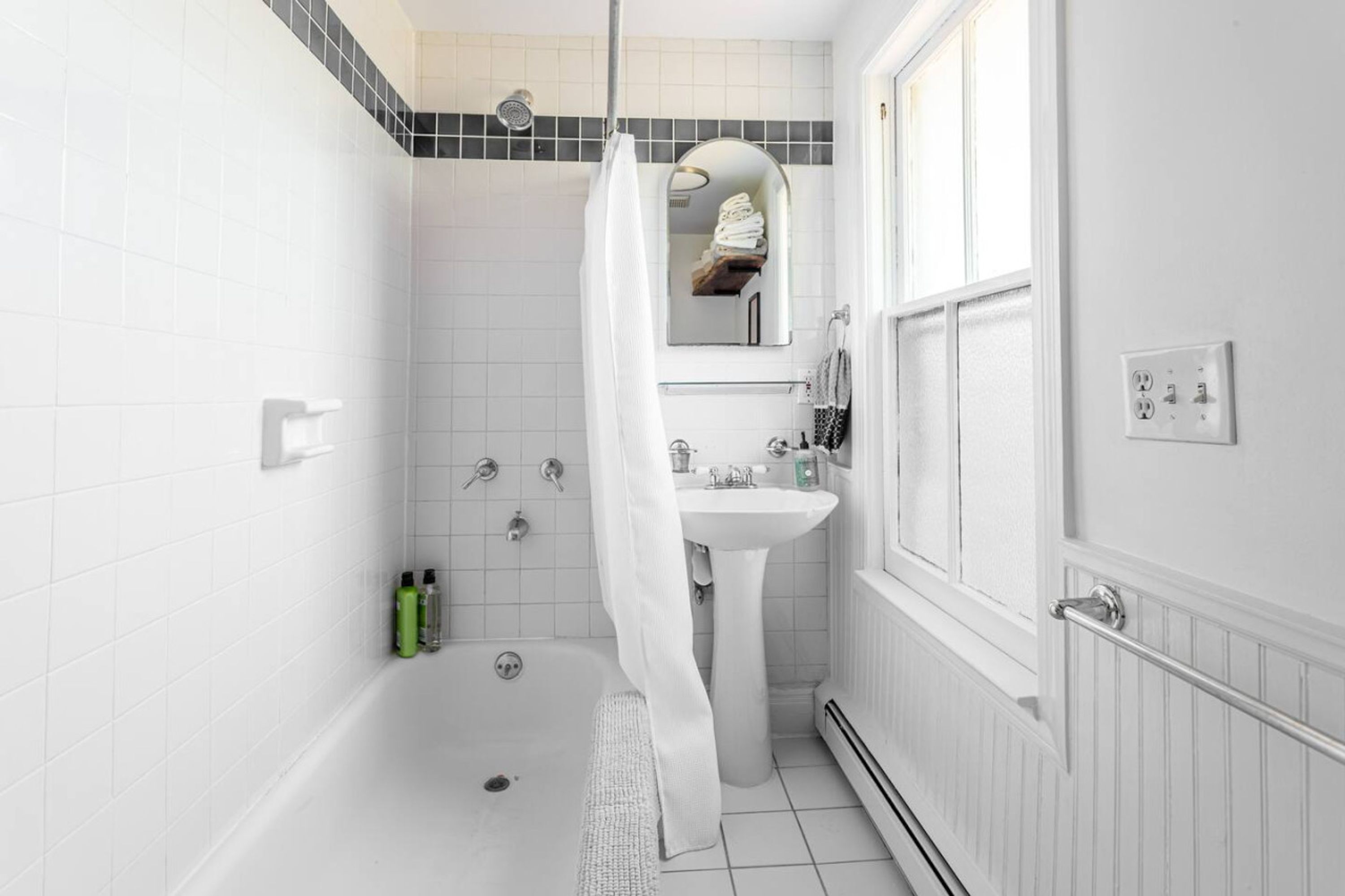 A modern bathroom with a bathtub, shower, and sink.