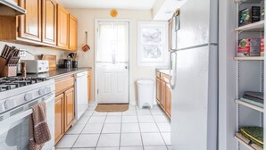 A kitchen with wooden cabinets, a stove, a refrigerator, and a window with a view. - Cozy Easy Access to the Best of the Hudson Valley (Cornwall)
