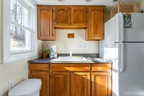 A kitchen with wooden cabinets, a white refrigerator, a sink, and a window. - Cozy Easy Access to the Best of the Hudson Valley (Cornwall)