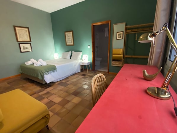 A bedroom with a bed, a desk, a chair, and a bathroom visible through an open door. - Porto Santo Destination (Porto Santo)