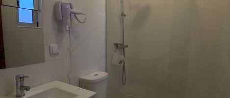 Un baño moderno con lavamanos, inodoro y ducha blancos.