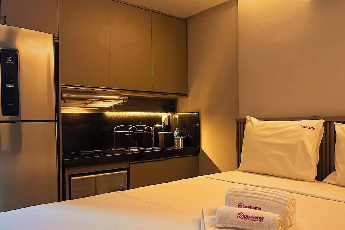 Une chambre d’hôtel avec un lit, une petite kitchenette et un réfrigérateur.