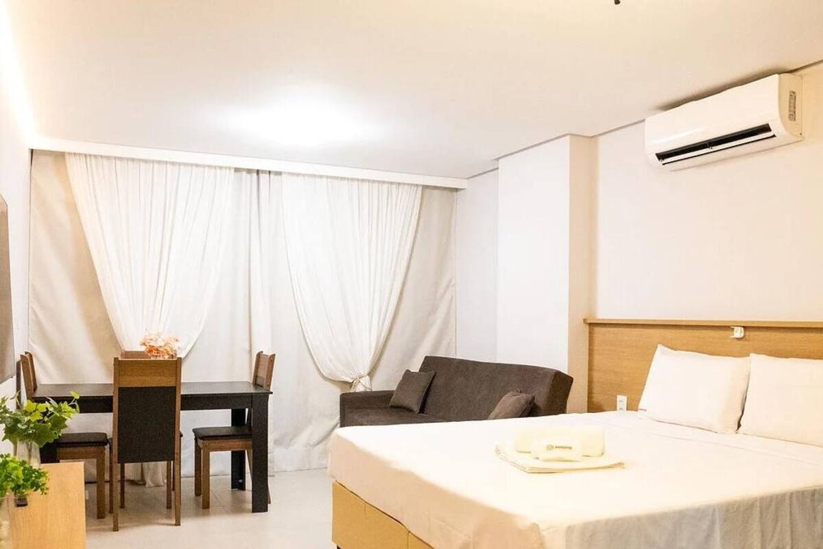 Une chambre d’hôtel comprenant un lit, un bureau avec des chaises, un canapé et un appareil de climatisation.